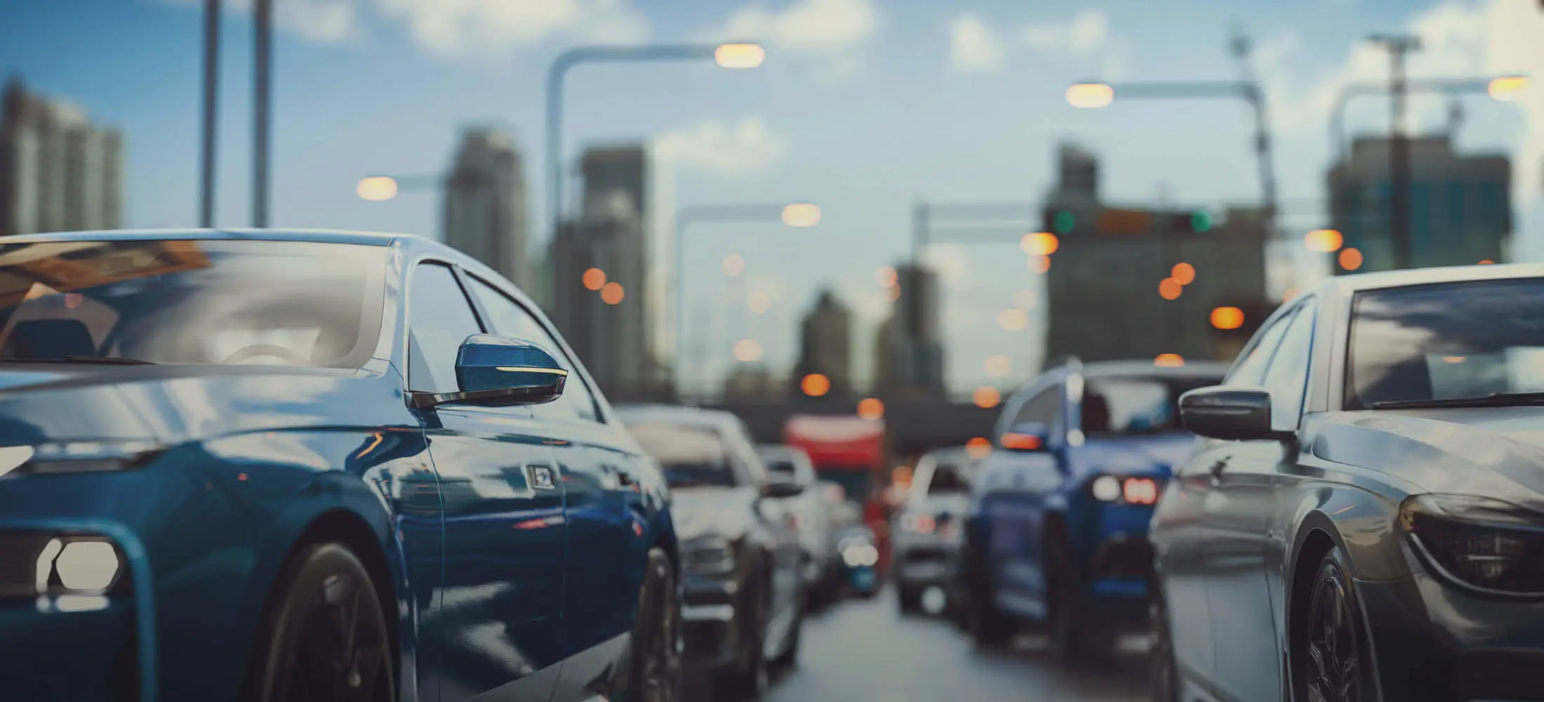 Viele Autos stehen dicht an dicht, im Hintergrund eine unscharfe Skyline und leuchtende Straßenlaternen.